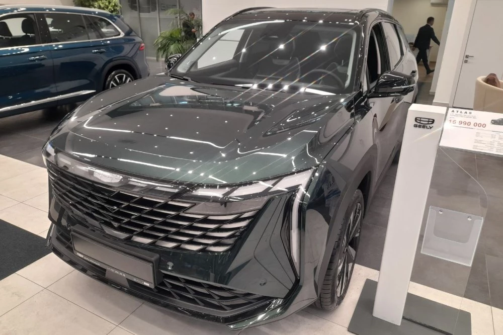 Geely Atlas нового поколения в Казахстане спереди сбоку в автосалоне