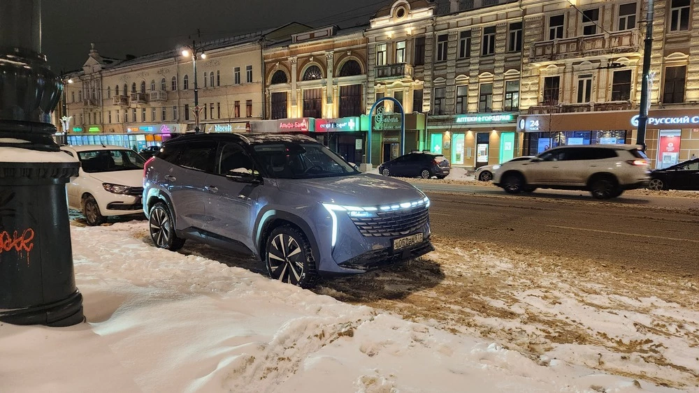 Кроссовер Geely Atlas сбоку спереди вечером