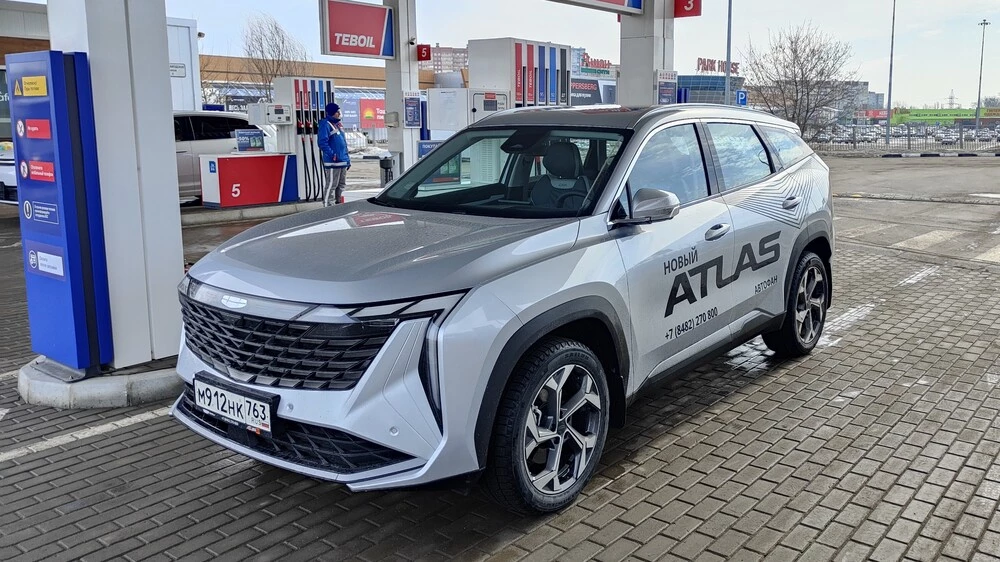Geely Atlas тест Мишина сбоку спереди на АЗС лючок заправка