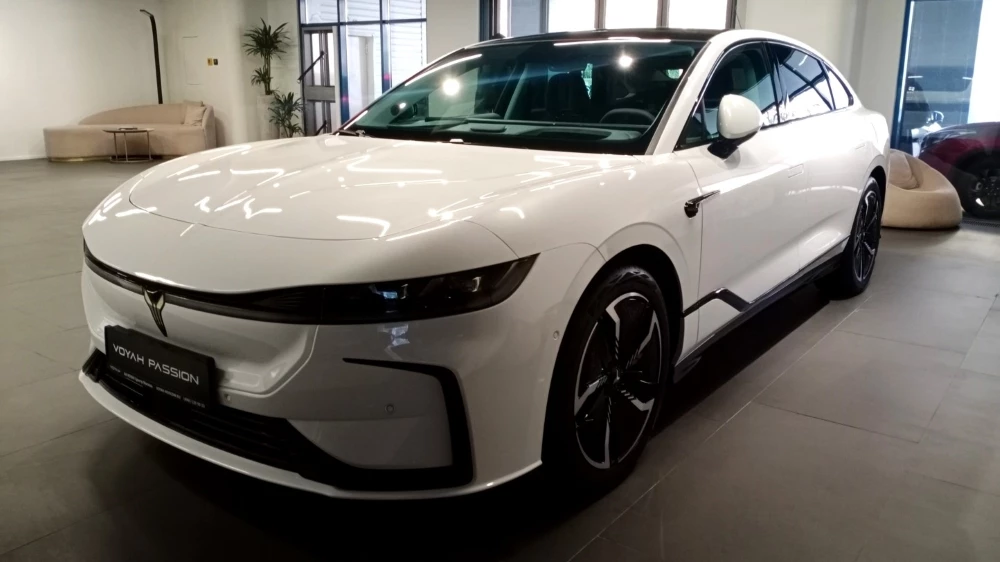 Электрический Voyah Passion у дилера сбоку спереди в автосалоне