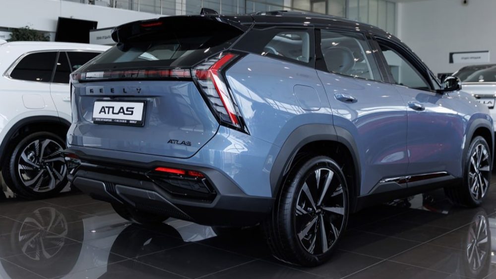 Geely Atlas бизнес кар у дилера в салоне сбоку сзади