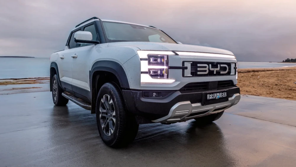 Австралийский журнал Wheels назвал BYD Shark 6 лучшим пикапом 2025 и 2026 годов сбоку спереди белый автомобиль