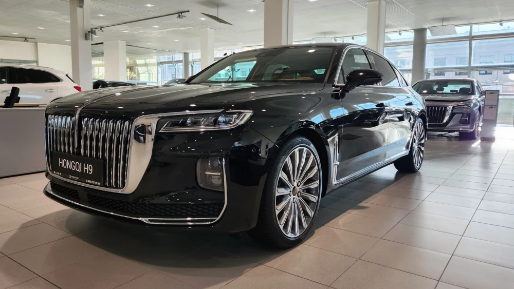 Седан Hongqi H9 в комплектации Deluxe сбоку спереди у дилера в автосалоне