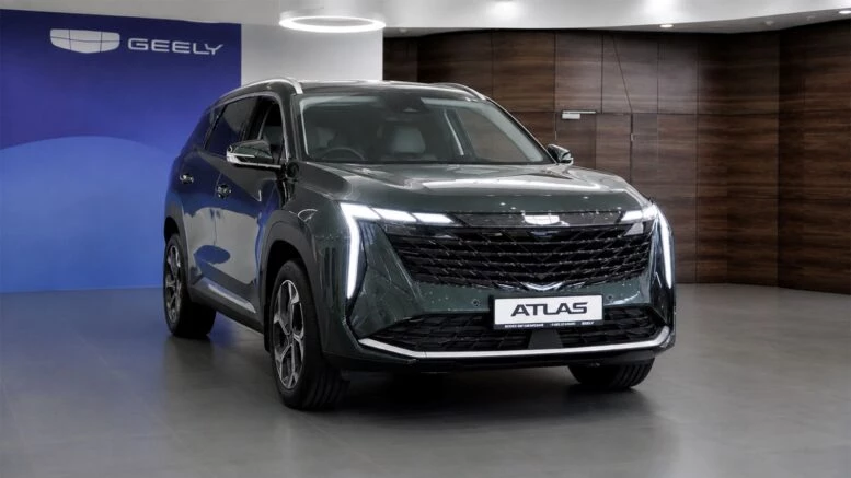 Geely Atlas: хватает ли переднего привода для жизни в мегаполисе? Geely Atlas Бизнес Кар сбоку спереди у дилера в автосалоне